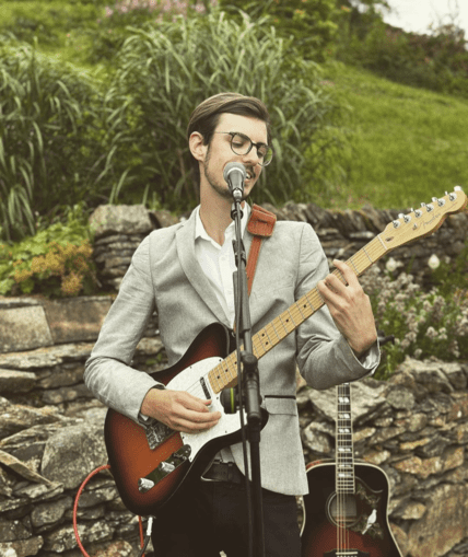 Person signing outside whilst playing the guitar