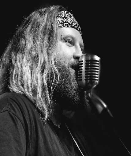 Black and white image of a person stood next to a microphone singing