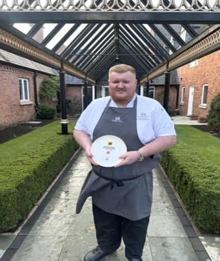 Chef stood outside holding an award they've won for cooking