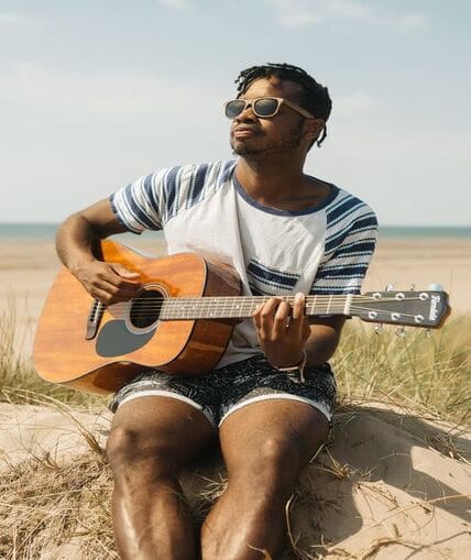 Person sat outside singing and playing their guitar