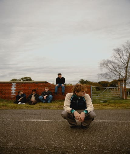A band of five sat outside with one member closer to the camera