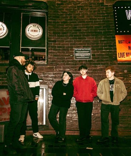 A band of five people stood taking promotional pictures
