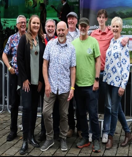 A large musical group stood outside smiling taking group shots