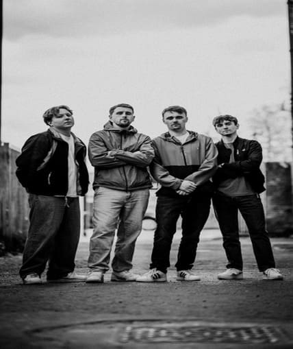 A black and white image of four band members stood outside