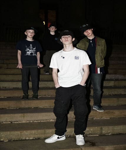 A group of four people stood outside on steps at night