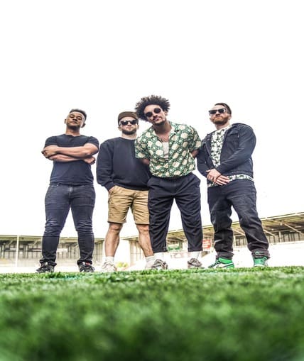 A band of four people stood on the pitch in a stadium