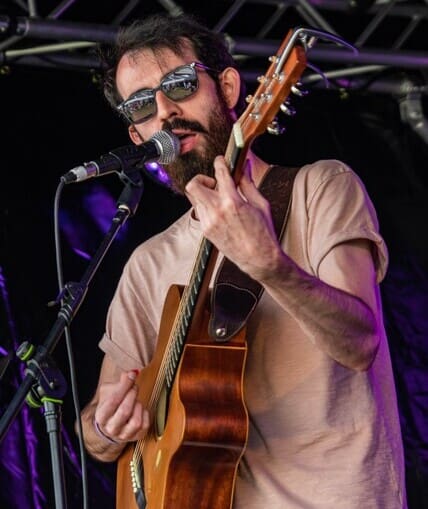 Performer holding a guitar and singing into a microphone