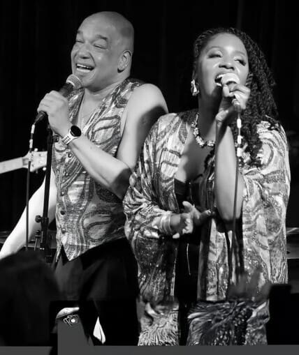 Image of two people singing on stage