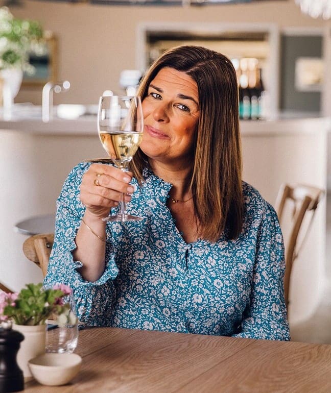 A woman sat at a dining table holding a glass of wine