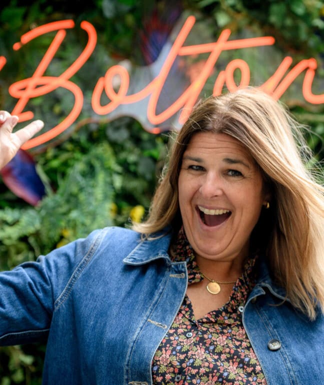 A woman pointing at a sign that says Bolton