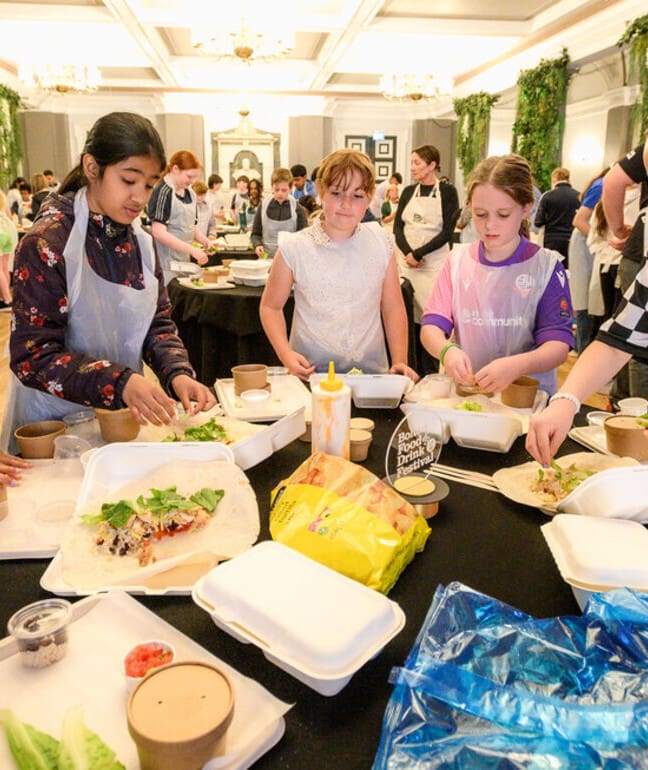 Three young people learning to cook a dish at a cooking demonstration