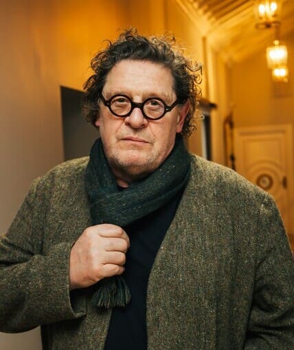 Person stood in hallway wearing a winter coat, holding their scarf