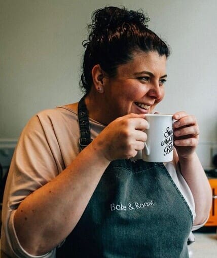 Cook wearing a apron holding a cup with two hands