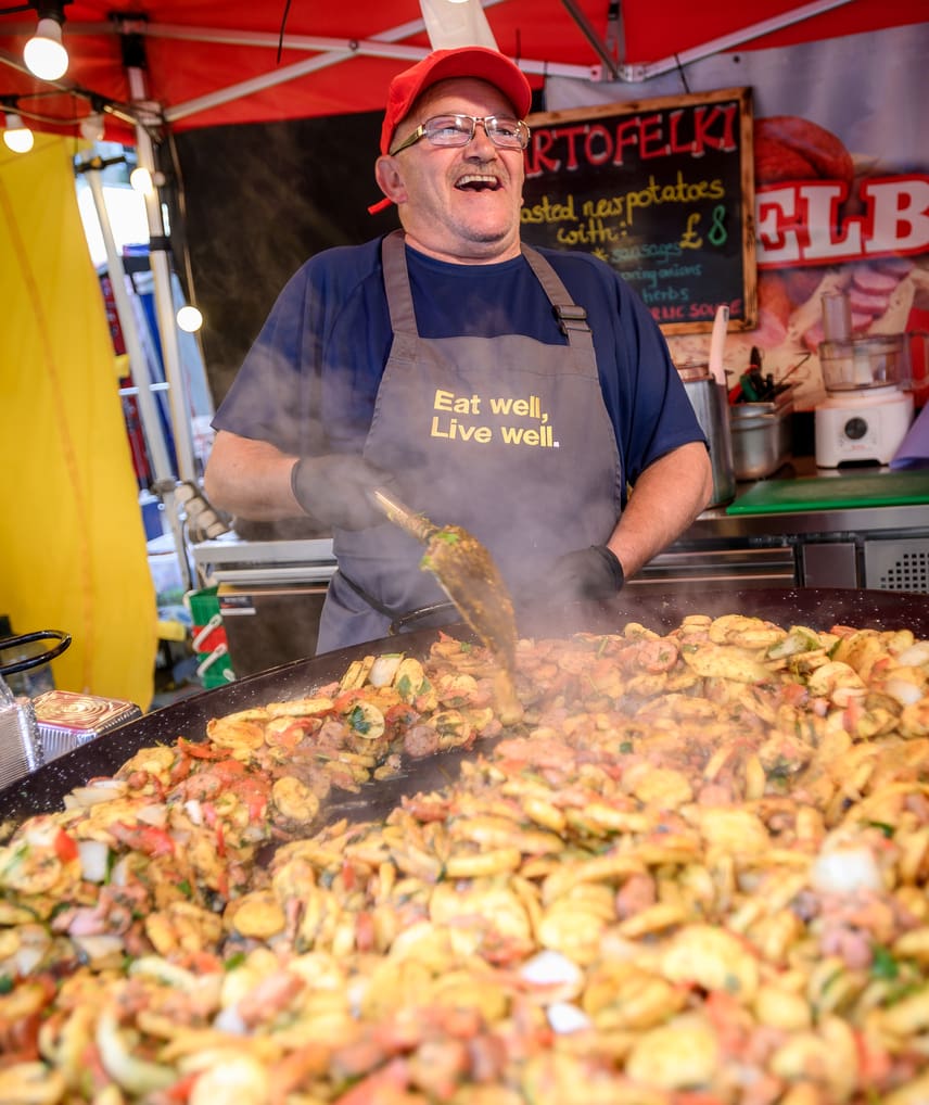 Cook making a large pan of food at market stall